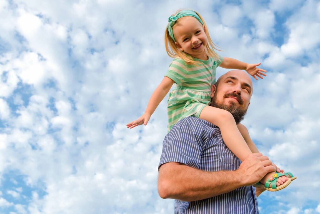 Smiling daughter on her father's shoulders after the family chooses to go solar